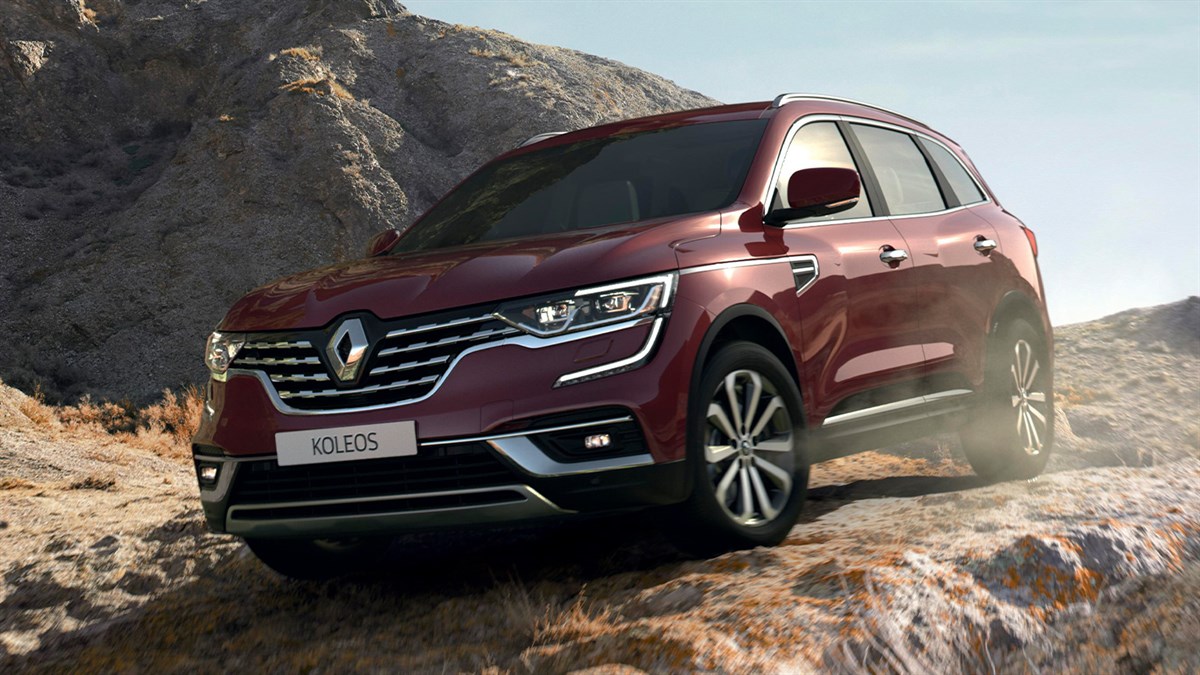 A front corner view of the wine-colored New Renault KOLEOS running slantier in the rocky hill